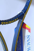Close-up detail of the inner racquet throat and shaft, showing the yellow Snauwaert branding and the text on the vintage paper warranty hang tag.