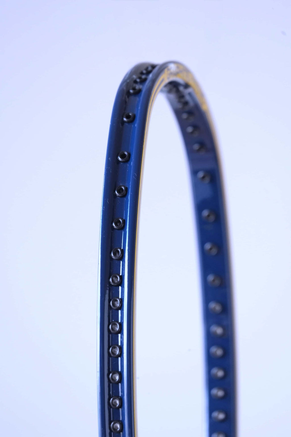 Close-up perspective shot of the empty string bed and black grommet strip running along the inside of the curved blue and yellow frame.