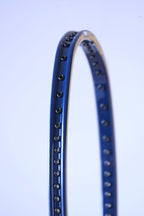 Close-up perspective shot of the empty string bed and black grommet strip running along the inside of the curved blue and yellow frame.