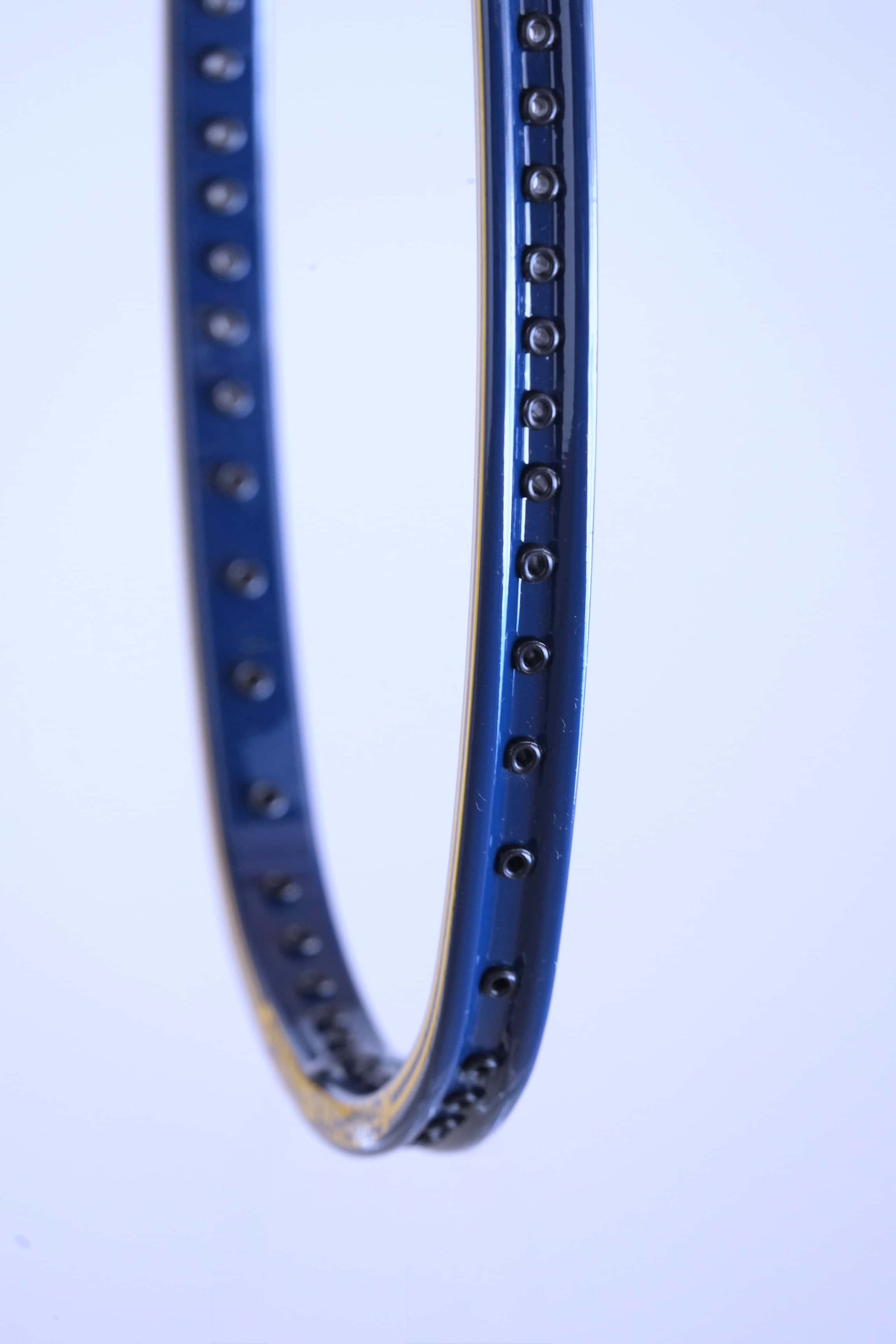 Close-up perspective shot of the empty string bed and black grommet strip running along the inside of the curved blue and yellow frame.