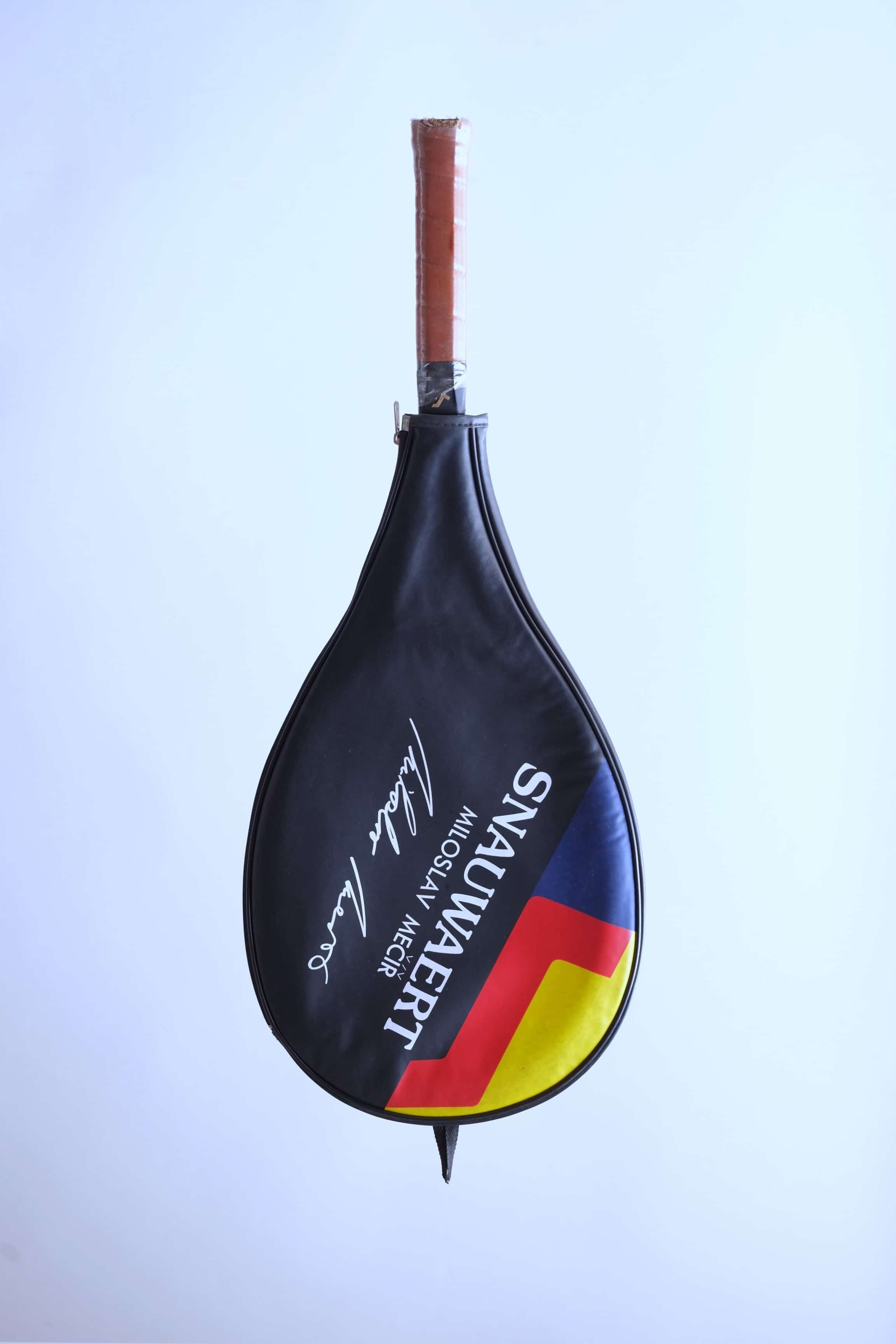 The vintage racquet inside its black protective cover, featuring the "SNAUWAERT" name, Miloslav Mečíř signature, and a red, yellow, and blue graphic.