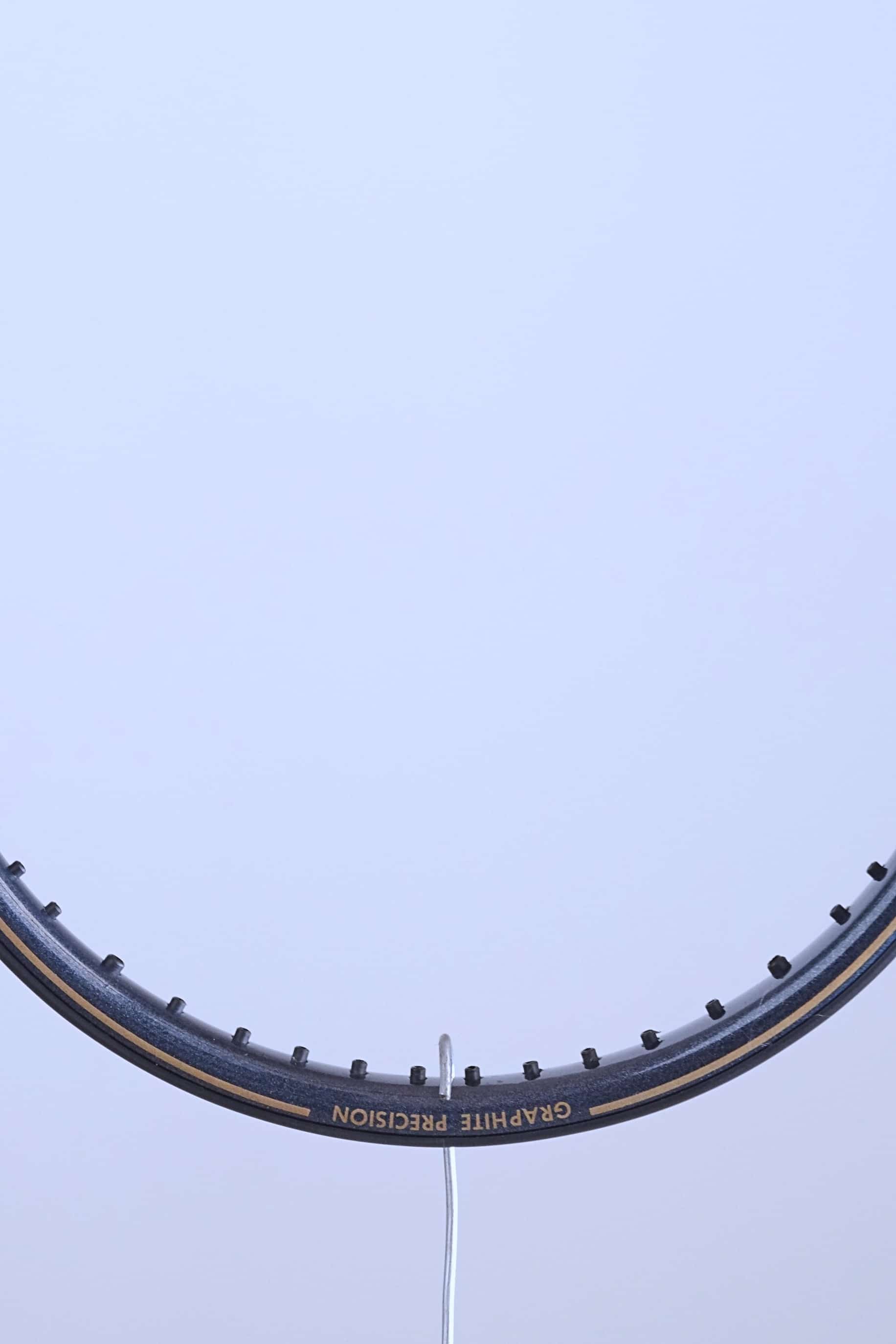 Close-up of the top curve of the racquet frame featuring the "GRAPHITE PRECISION" model name in gold lettering.