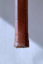 Detailed view of the bottom of the racquet handle, showing the worn leather and clear protective wrap at the base.