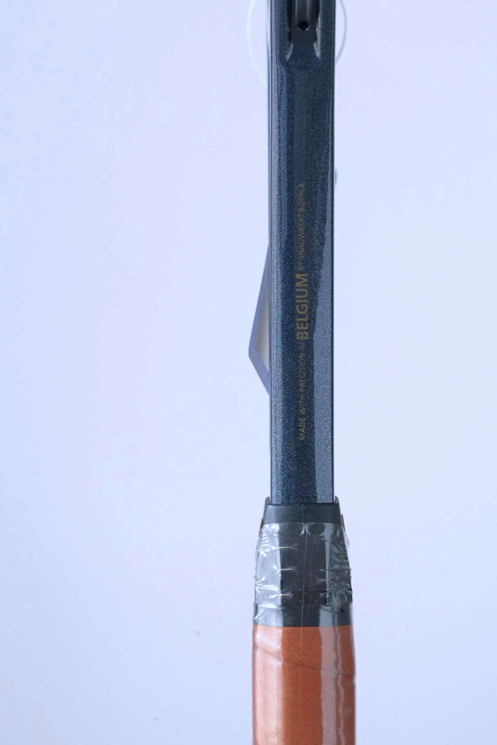 Detail of the racquet shaft above the grip, showing the gold text "MADE WITH PRECISION IN BELGIUM BY SNAUWAERT & DEPLA".