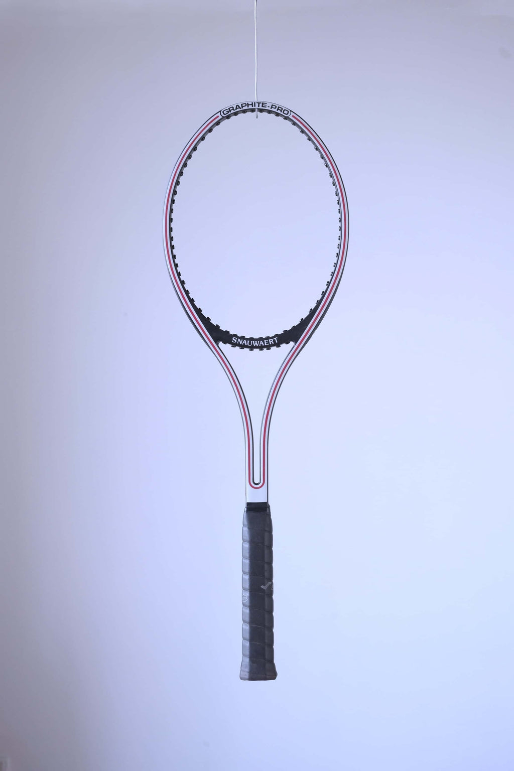 Studio full shot of an unstrung black and white Snauwaert Graphite Pro tennis racquet suspended against a plain white backdrop.