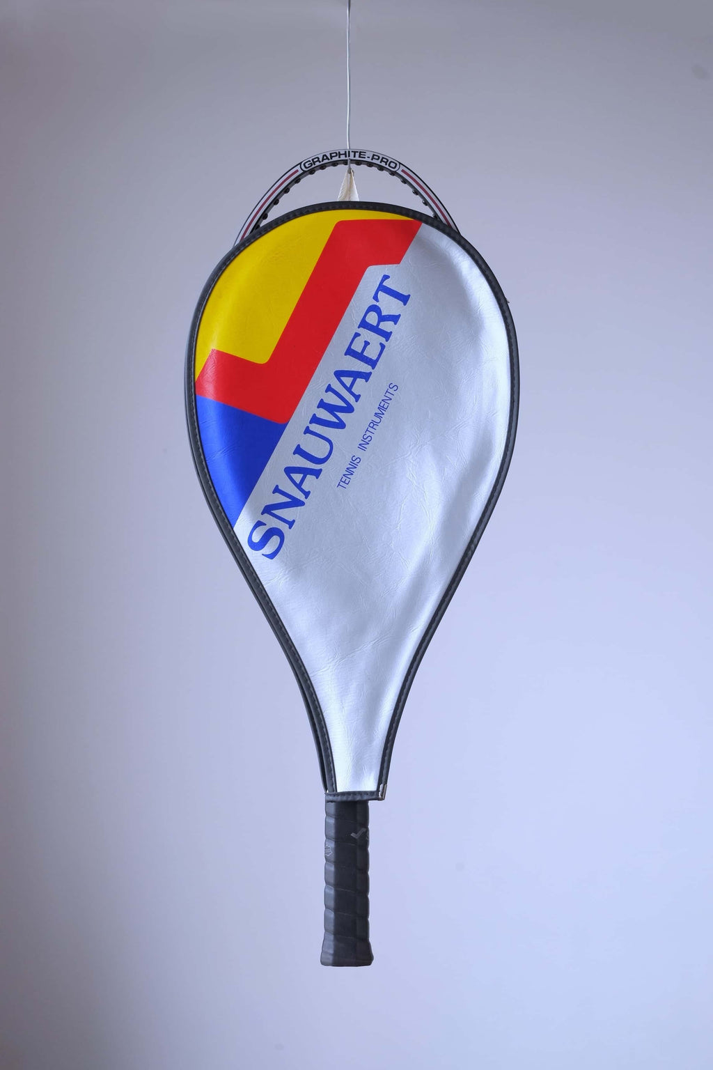 The vintage racquet head enclosed in its original silver vinyl Snauwaert cover with bold blue, red, and yellow accents.