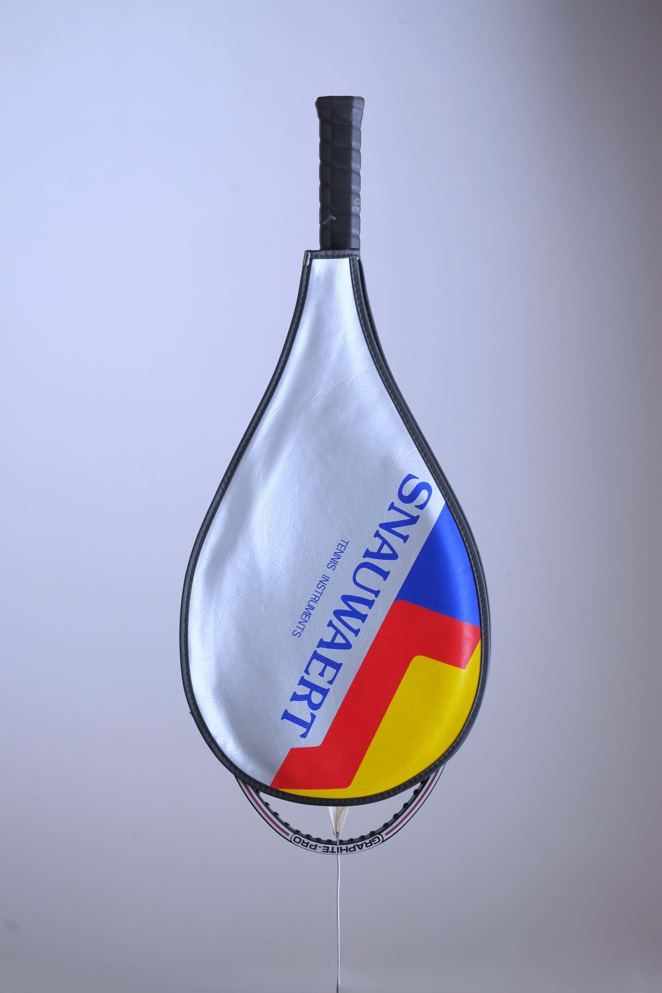 The vintage racquet head enclosed in its original silver vinyl Snauwaert cover with bold blue, red, and yellow accents.