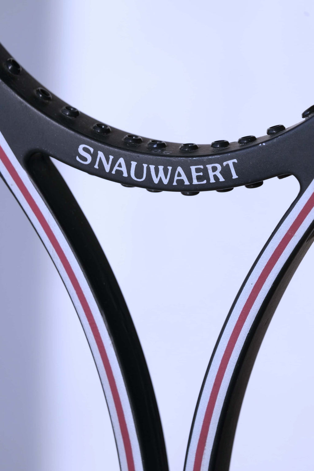 Close-up of the inner racquet throat showcasing the white "SNAUWAERT" text printed on the black bridge piece.