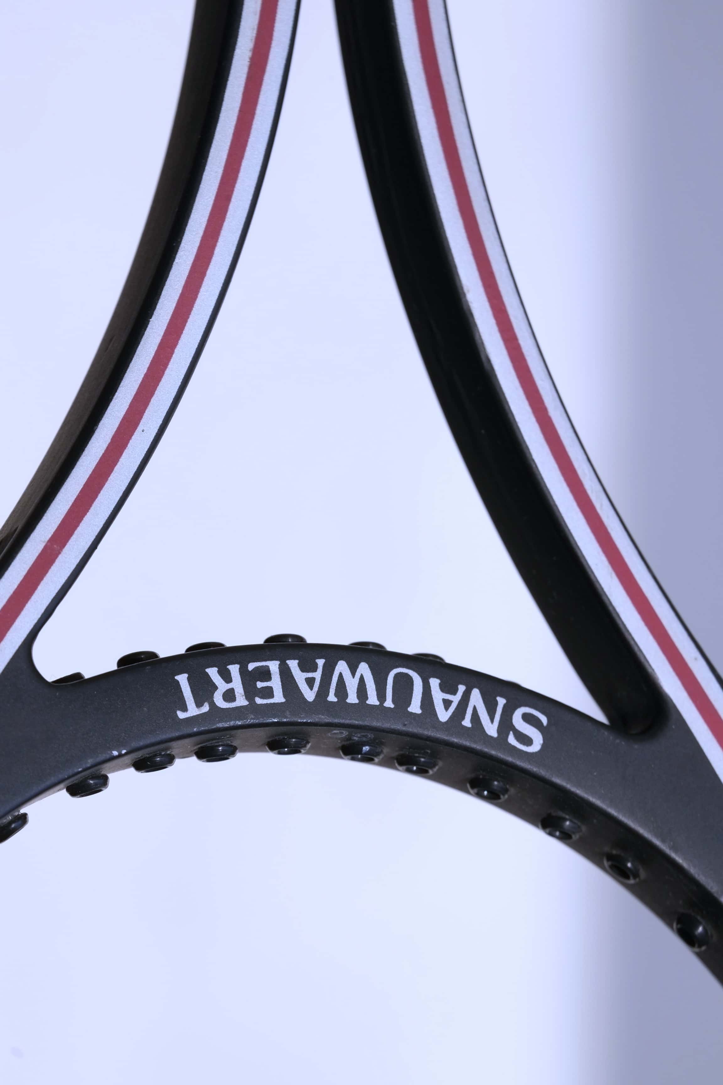 Close-up of the inner racquet throat showcasing the white "SNAUWAERT" text printed on the black bridge piece.