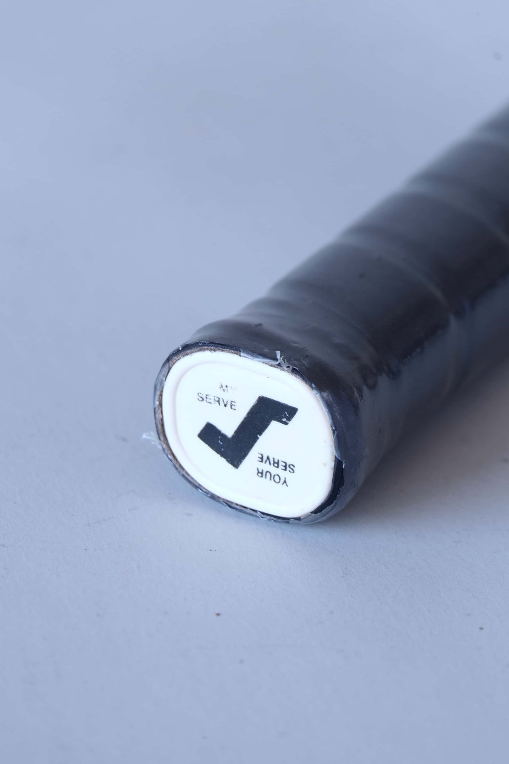 Close-up of the white plastic handle butt cap on a vintage squash racket featuring the black stylized Snauwaert logo.