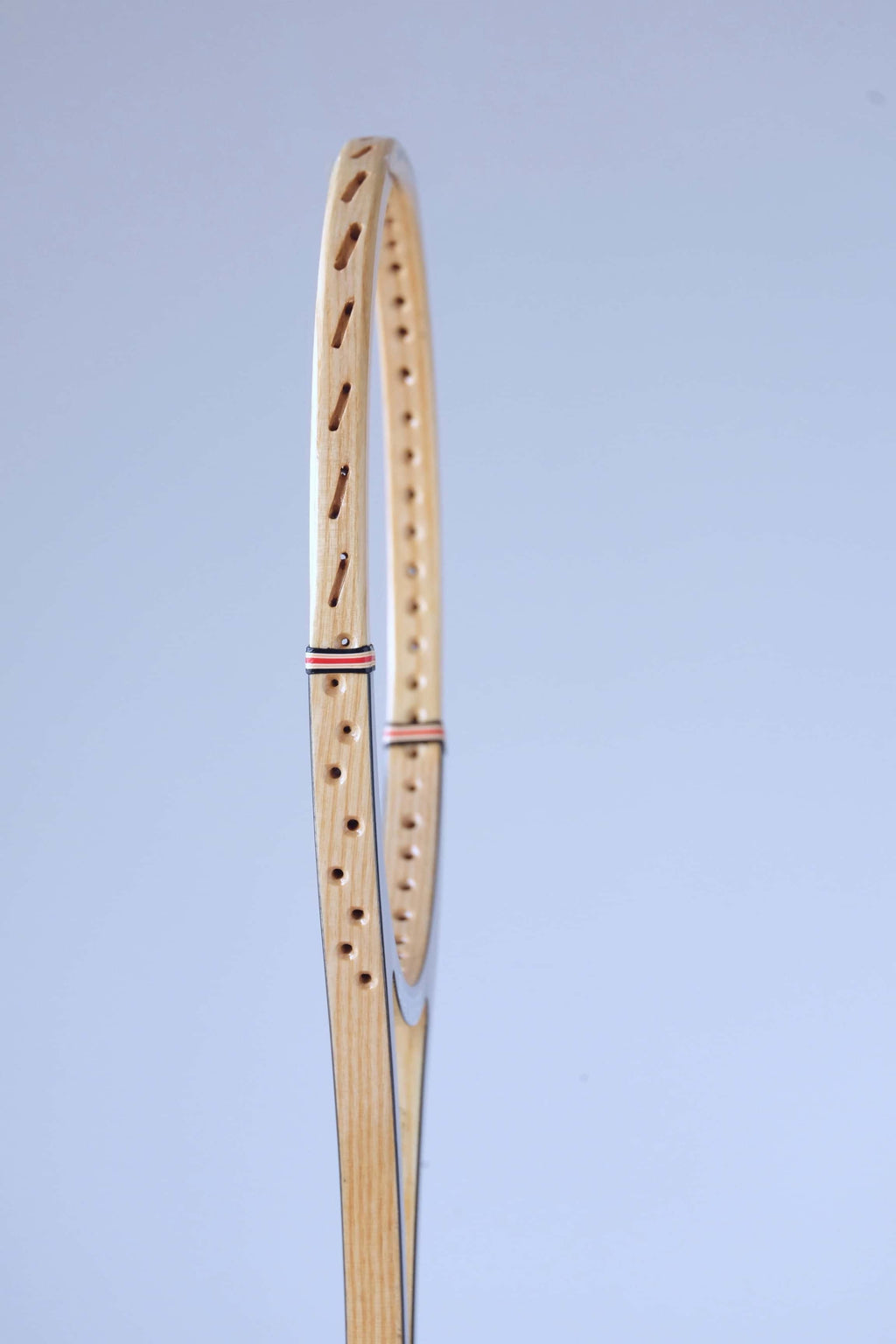 Profile close-up of the wood laminate frame and pre-drilled string holes of a vintage Snauwaert squash racket.
