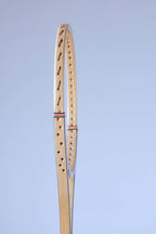 Profile close-up of the wood laminate frame and pre-drilled string holes of a vintage Snauwaert squash racket.
