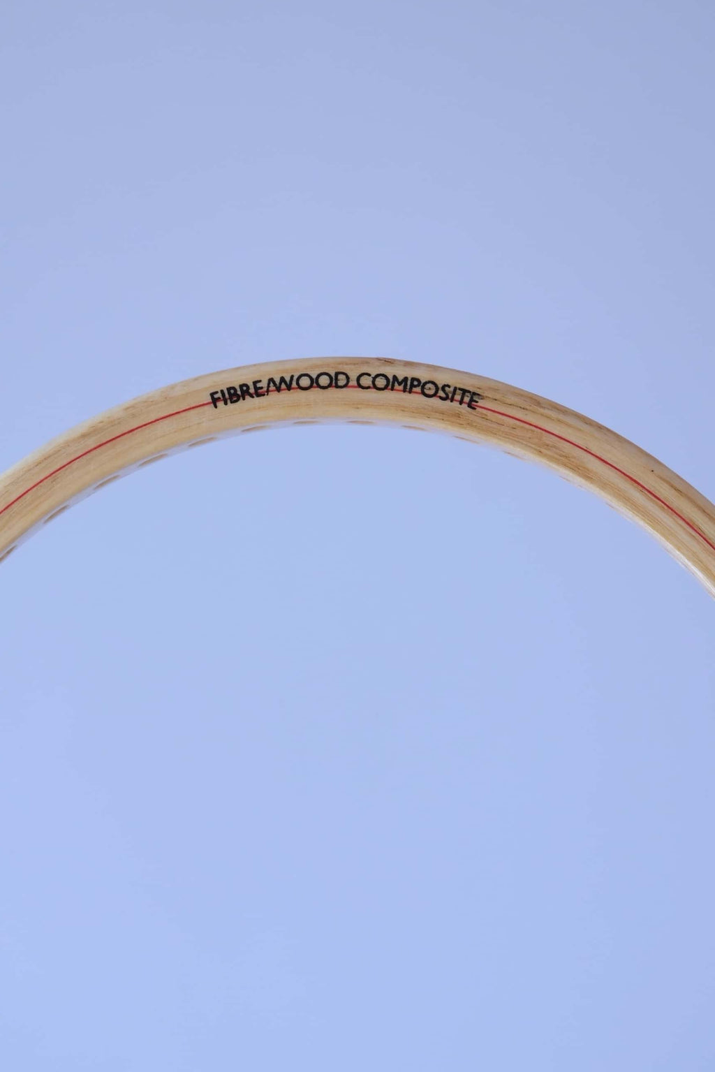 Close-up of the top curve of a vintage wood squash racket frame showing the text Fibre Wood Composite.