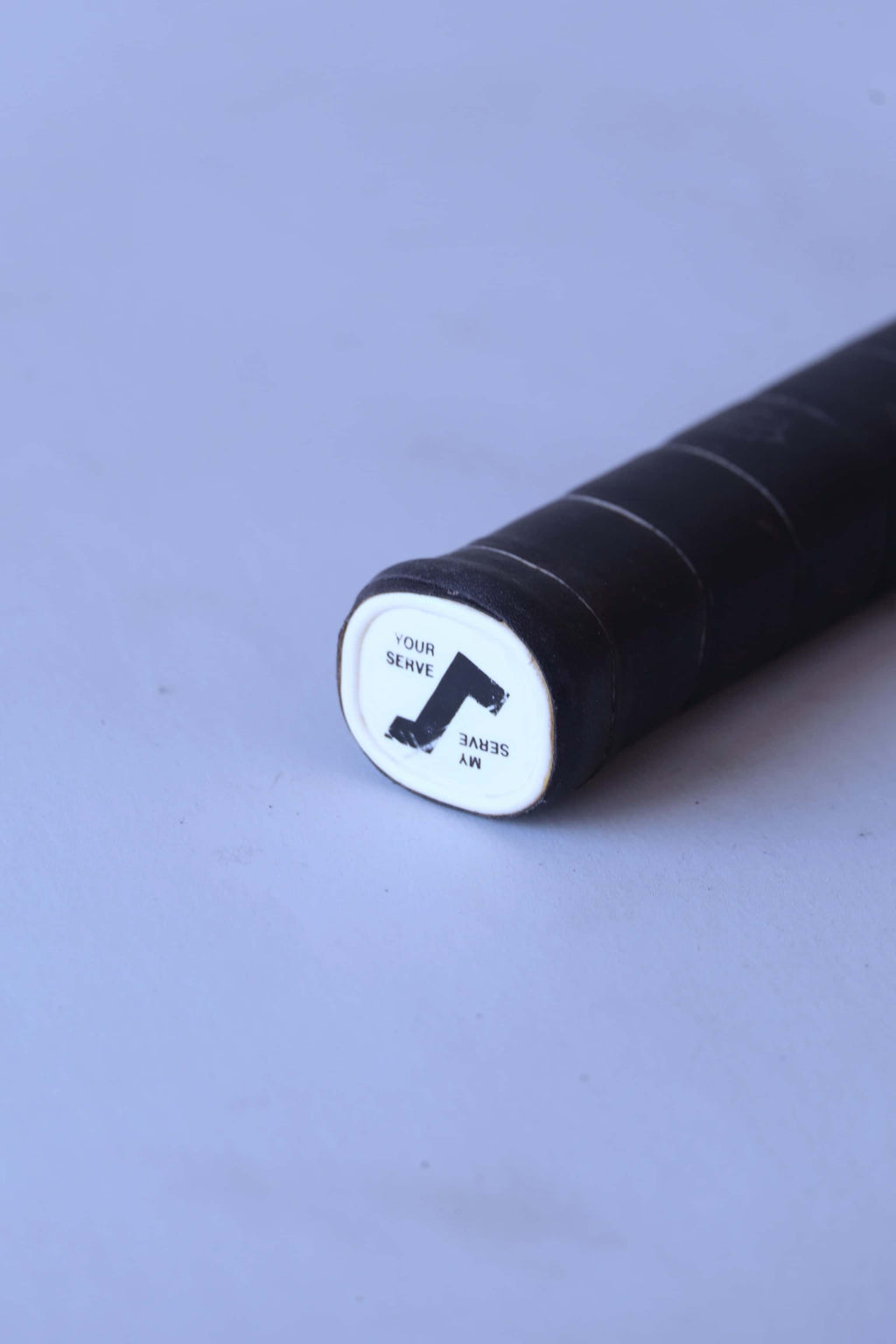 Close-up of the white plastic butt cap on a vintage squash racket handle featuring a black Snauwaert logo and the words Your Serve and My Serve.