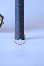 Close-up of a squash racket handle with a red circle highlighting a small nick of wear at the very bottom edge of the black leather grip.