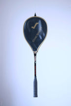 Vintage Snauwaert Pistol squash racket hanging vertically inside its original black and gold zippered vinyl cover.