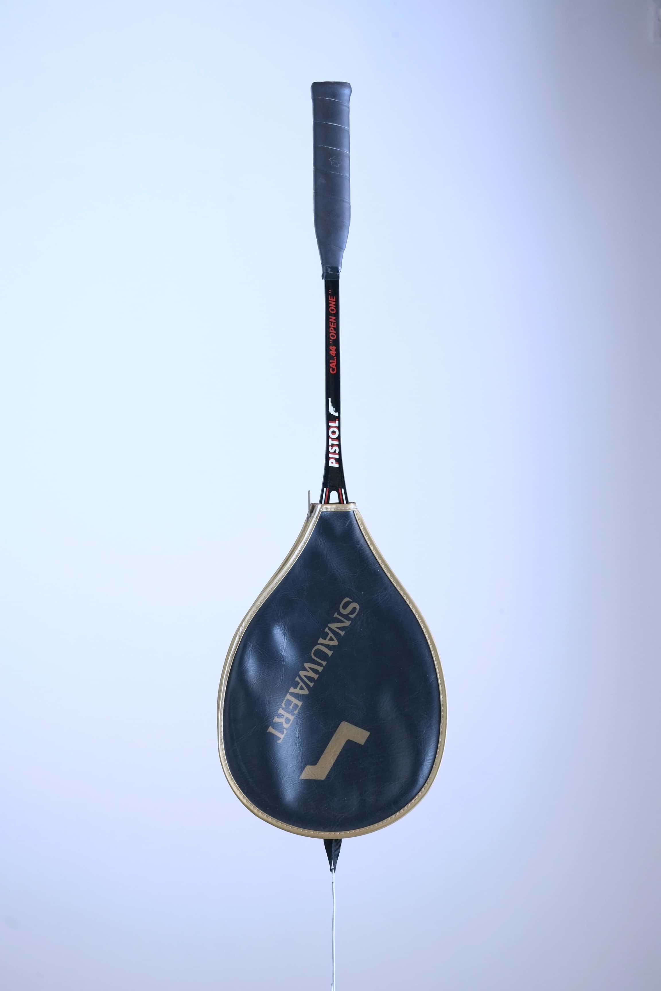 Vintage Snauwaert Pistol squash racket hanging vertically inside its original black and gold zippered vinyl cover.
