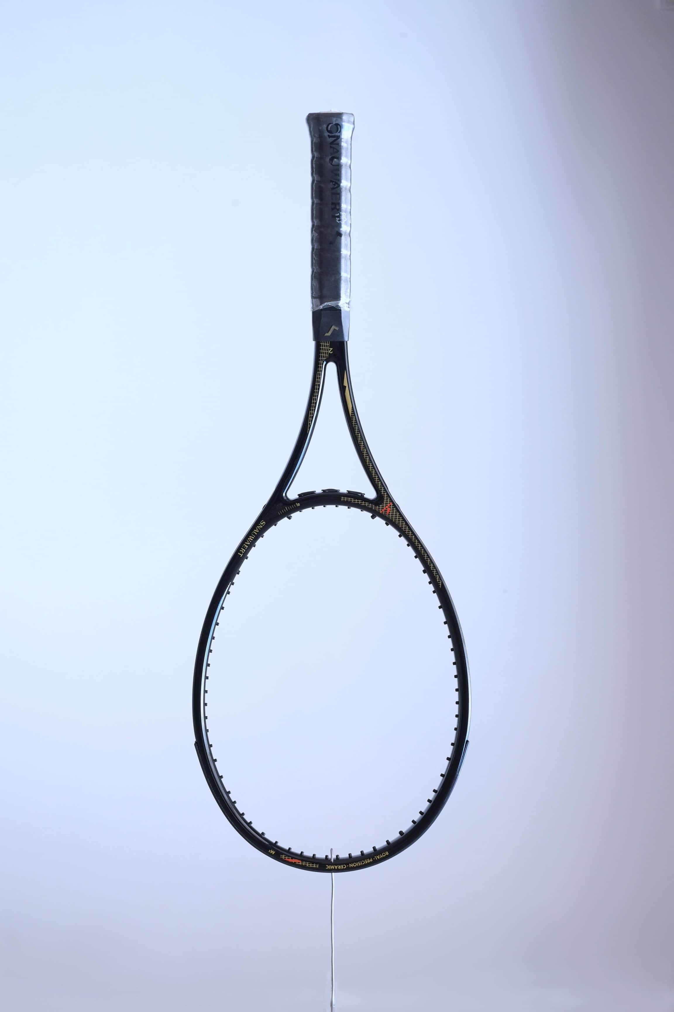 Studio full front shot of an unstrung black Snauwaert Royal Precision Ceramic tennis racquet with a grey grip and gold accents.