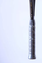 Close-up of the racquet shaft above the grip, showing the gold text "MADE WITH PRECISION IN BELGIUM BY SNAUWAERT" and serial numbers.