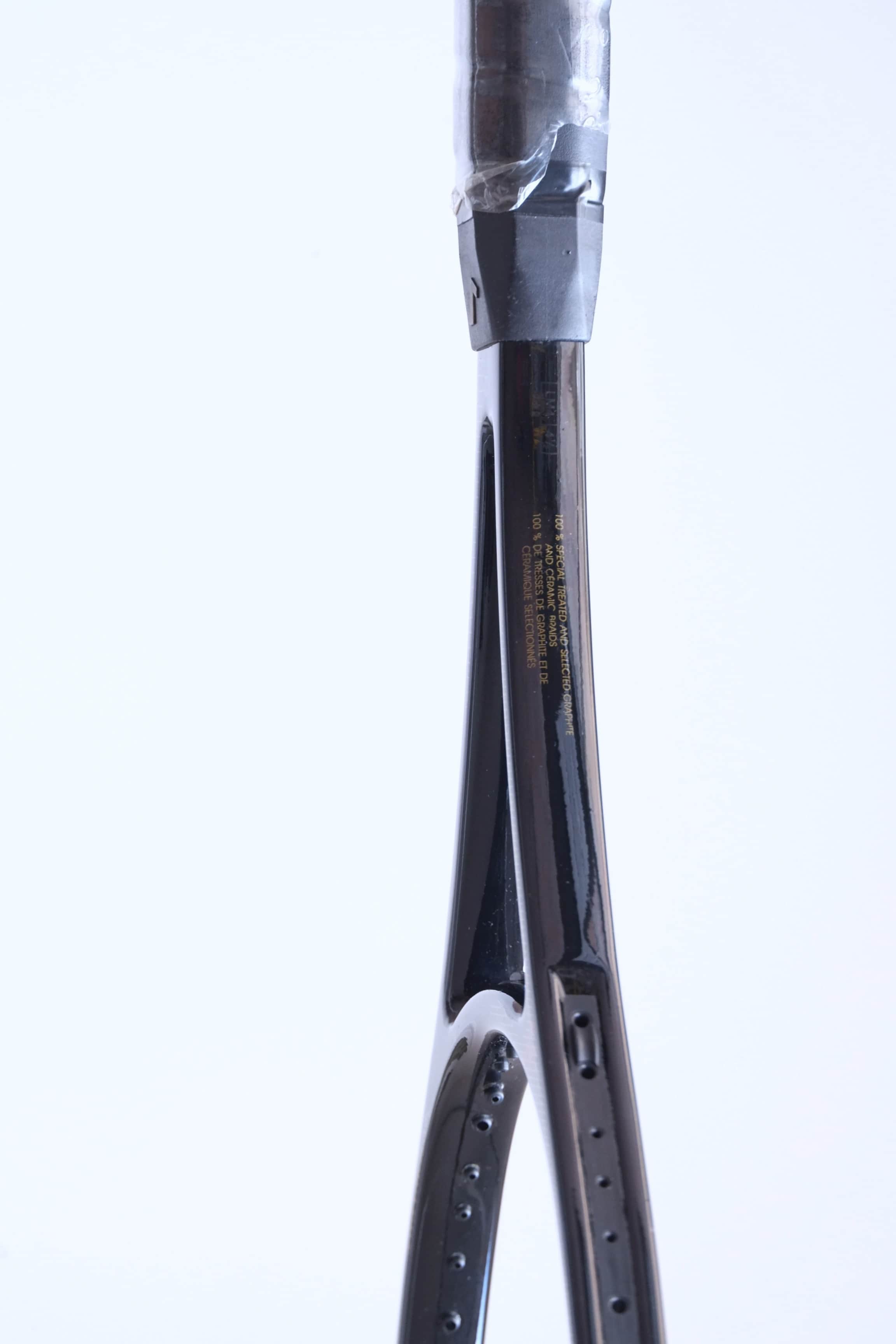 Profile shot of the racquet shaft detailing the material composition: "100% SPECIAL TREATED AND SELECTED GRAPHITE AND CERAMIC RAIDS".