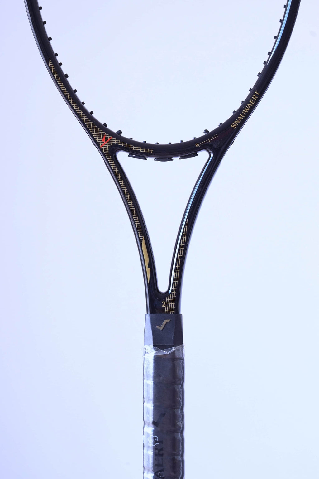 Frontal close-up of the racquet throat showcasing the gold "SNAUWAERT" name, pinstripe detailing.