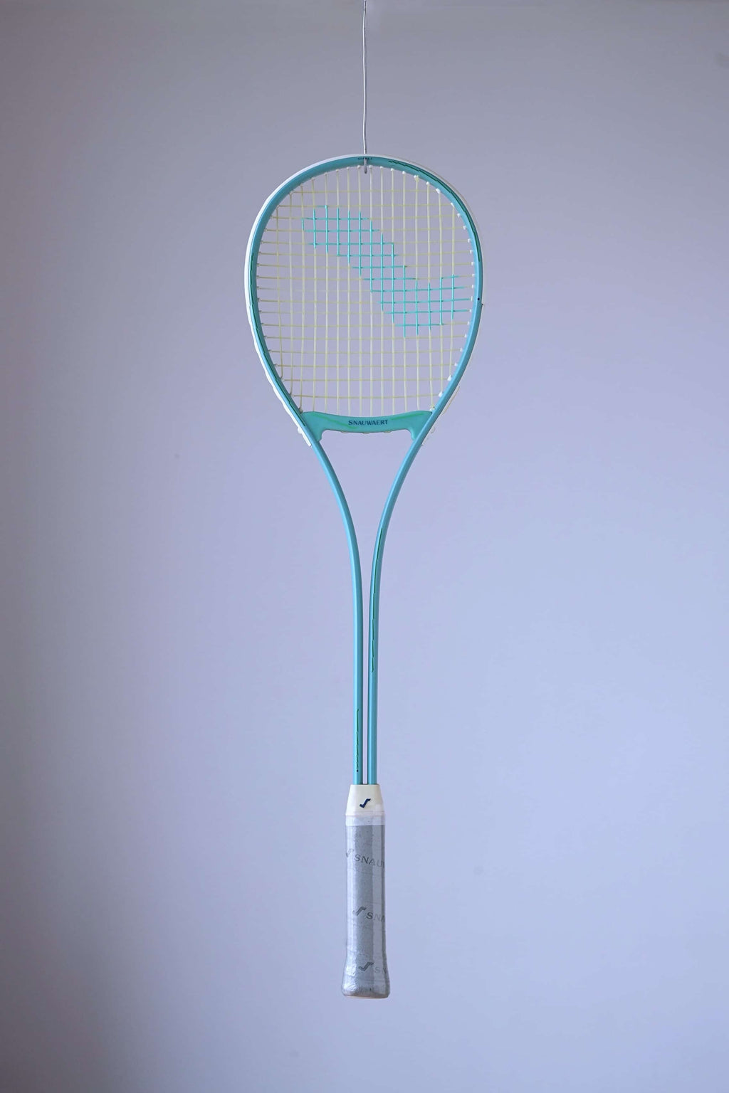 Snauwaert Shark 2 vintage squash racquet suspended against a light background, showing full teal frame, teardrop head and grey branded grip wrap.