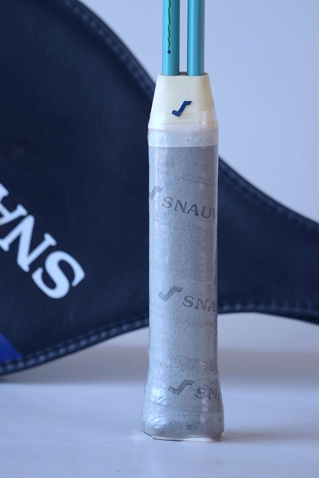 Close-up of the Snauwaert Shark 2 squash racquet grip showing original grey Snauwaert branded wrap, white throat piece and Snauwaert shield cover in background.