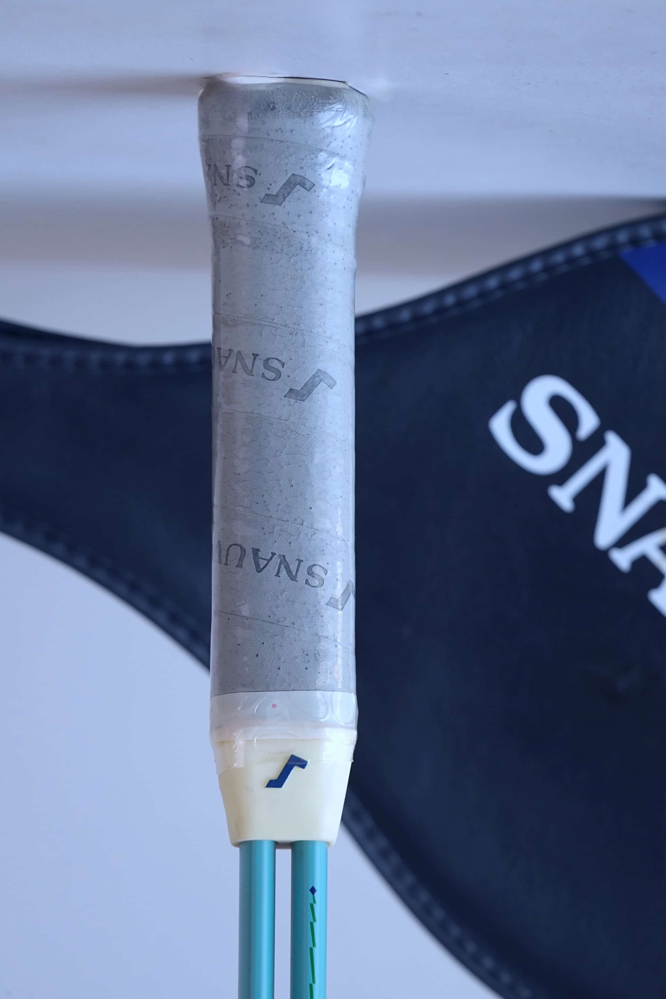 Close-up of the Snauwaert Shark 2 squash racquet grip showing original grey Snauwaert branded wrap, white throat piece and Snauwaert shield cover in background.