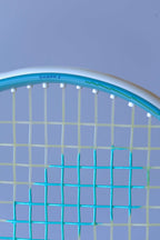 Close-up of the Snauwaert Shark 2 squash racquet head showing white grommets, teal and yellow-green string pattern and Shark 2 model name printed on the frame.