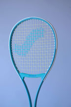 Angled front view of the Snauwaert Shark 2 squash racquet head showing teal and white frame, Snauwaert throat bridge and teal cross-string pattern on yellow-green mains.