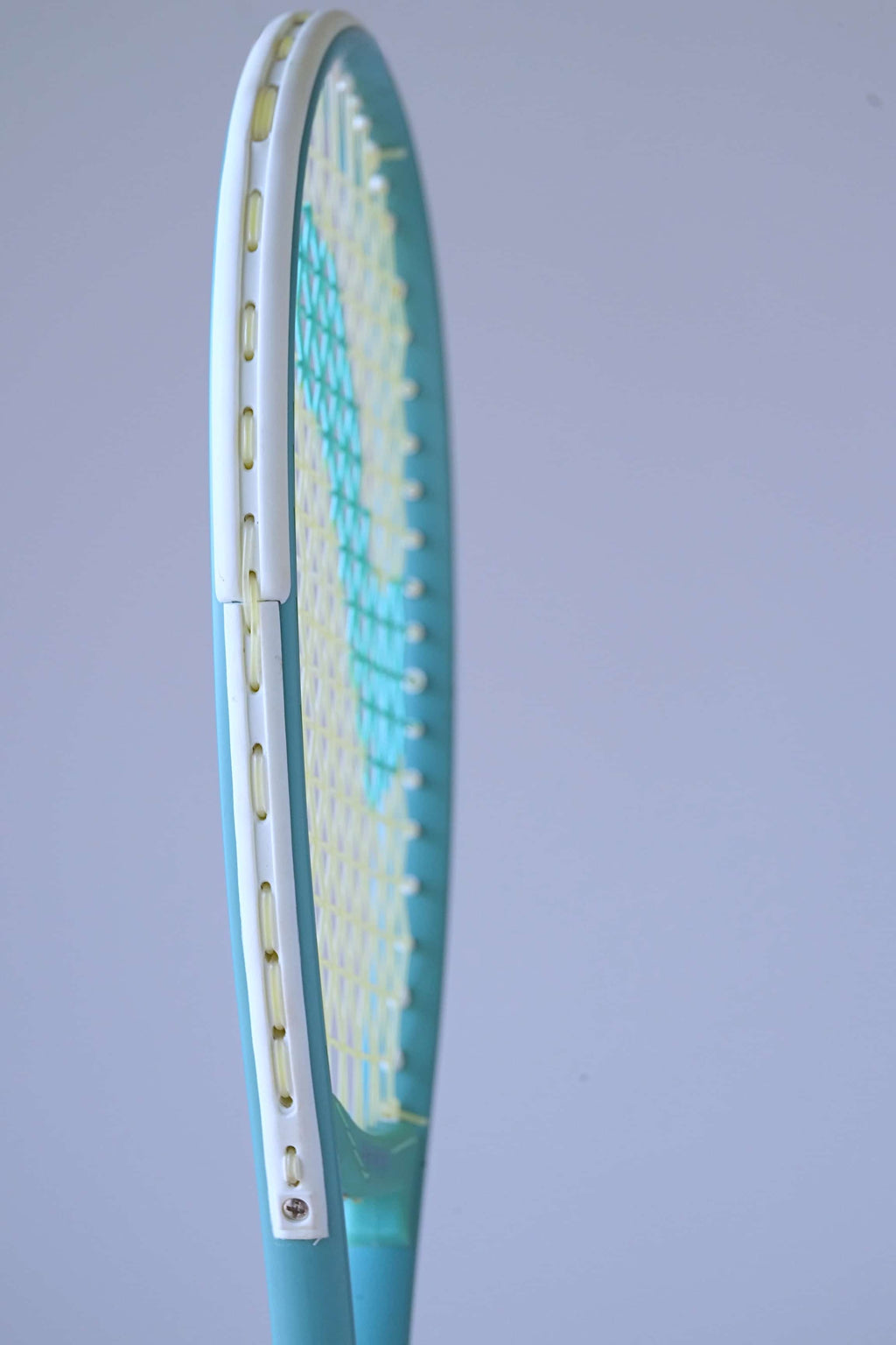 Side profile of the Snauwaert Shark 2 squash racquet head showing white bumper strip, teal frame and yellow-green string bed.