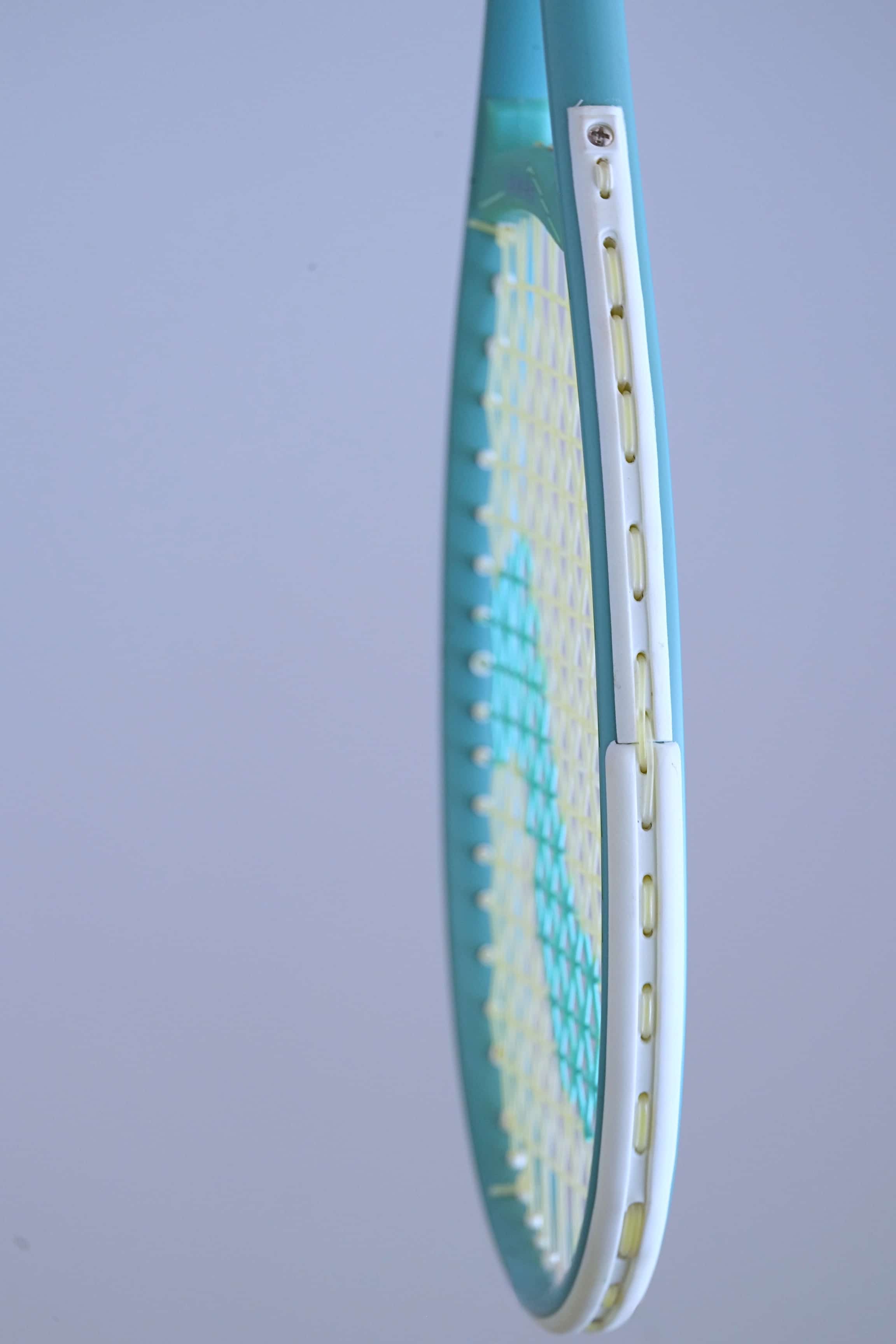 Side profile of the Snauwaert Shark 2 squash racquet head showing white bumper strip, teal frame and yellow-green string bed.