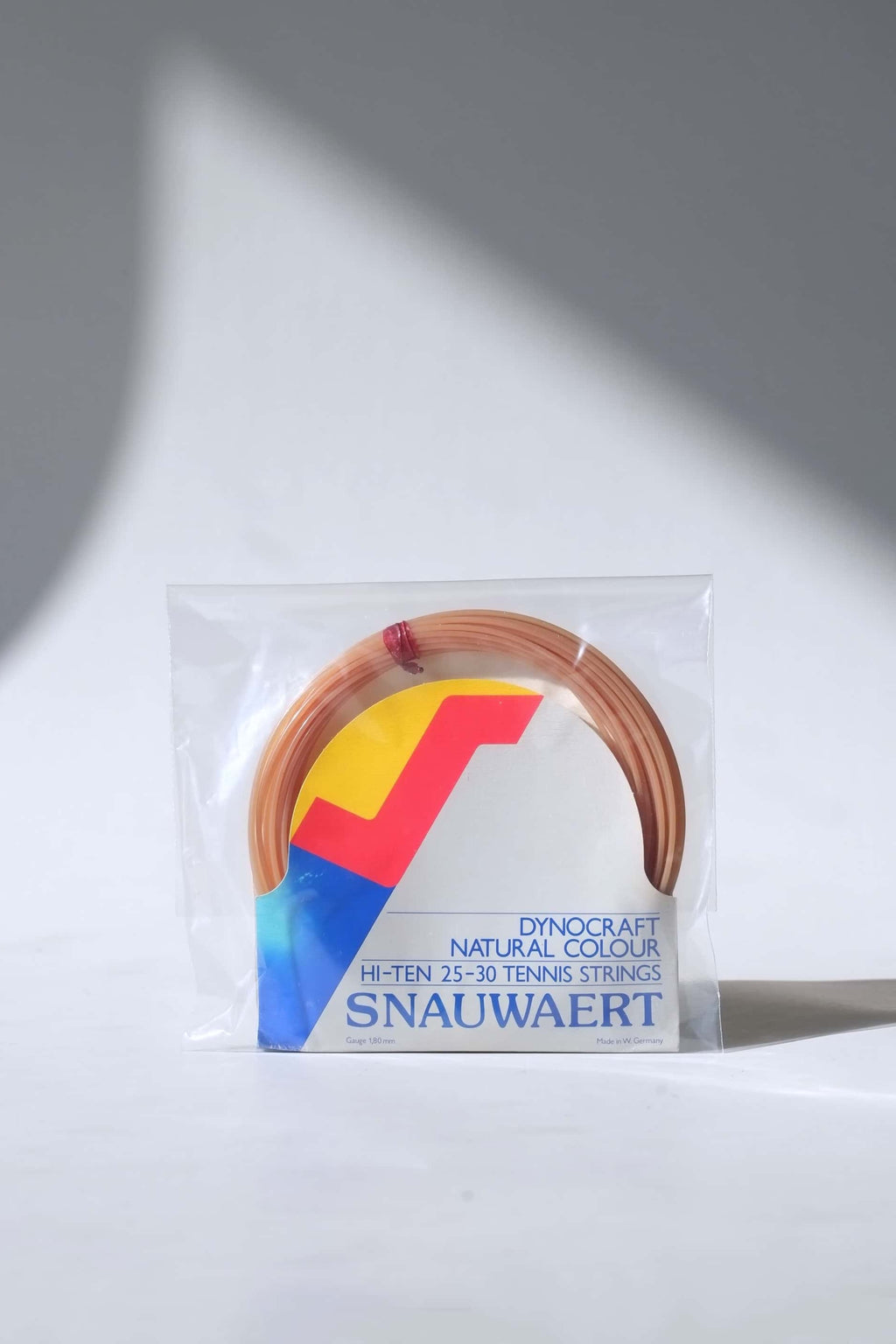 Deadstock vintage Snauwaert Dynocraft Hi-Ten 25-30 tennis strings in their original grey, yellow, and red and blue retail sleeve packaging.