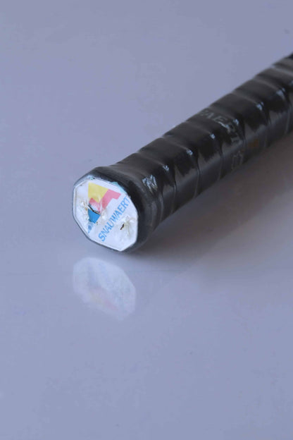 Close-up of a tennis racket handle with a black grip wrapped in plastic, and a blue,
 yellow, and red SNAUWAERT logo.