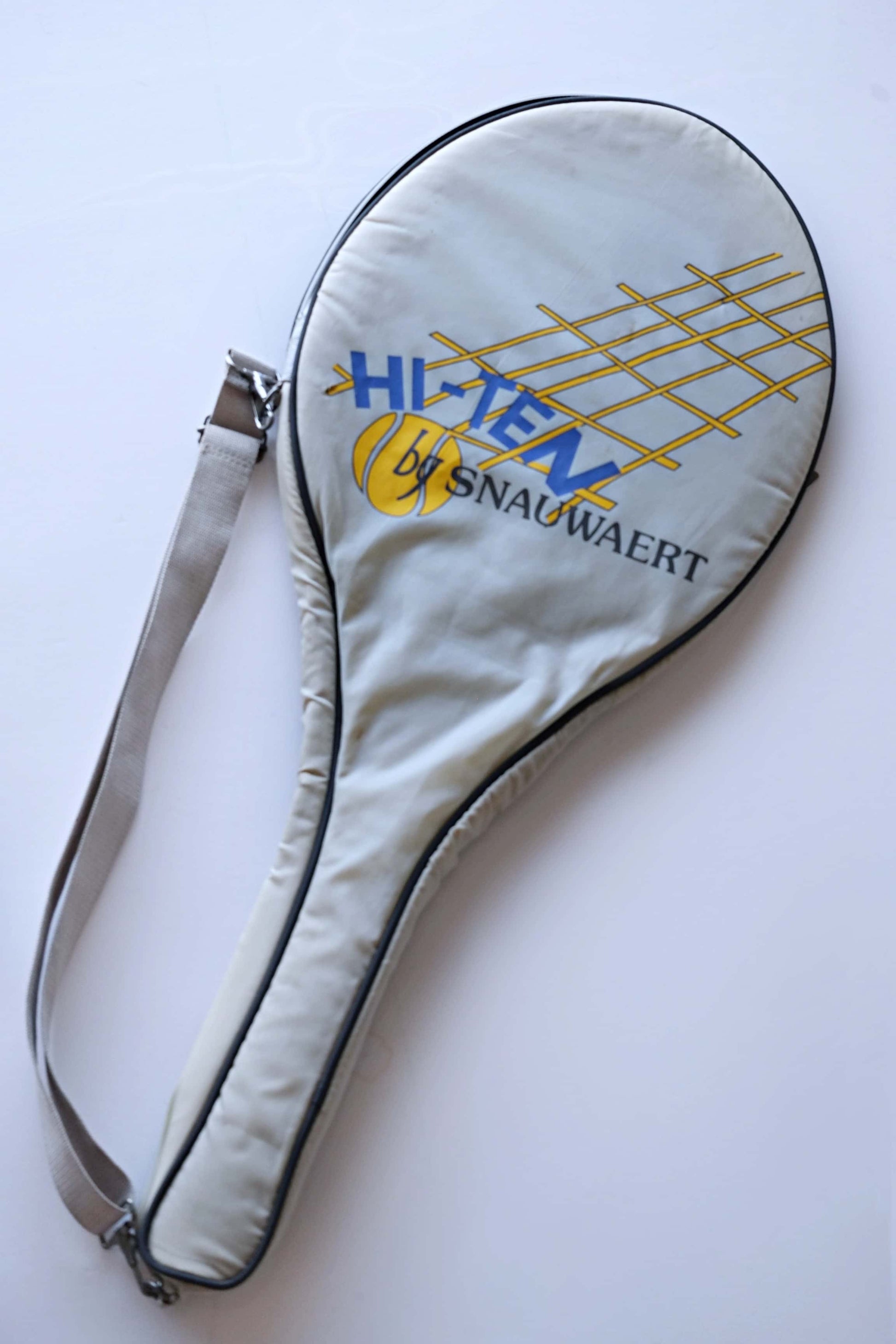 Vintage Tennis racquet cover for the Hi-Ten by Snauwaert. It's light grey with a yellow and blue logo.
 The cover has a shoulder strap attached to it.