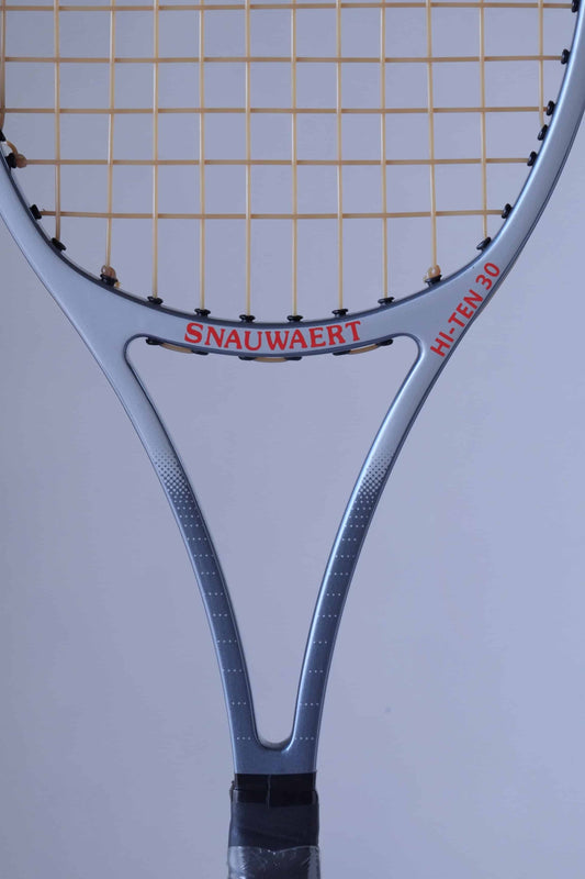 Close-up of the throat area of a Snauwaert Hi-Ten 30 tennis racket, highlighting the red Snauwaert logo and model name in bold lettering on the grey frame.