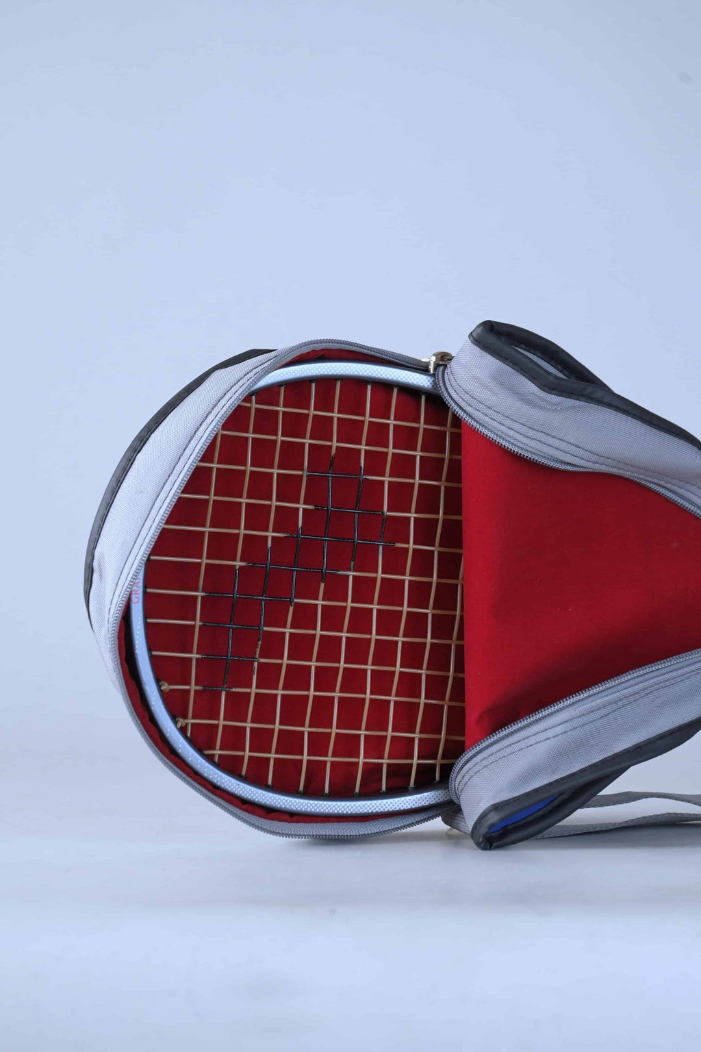 Inside view of the vintage Snauwaert racket bag, showcasing the red interior lining and zipper construction, with a racket inside.
