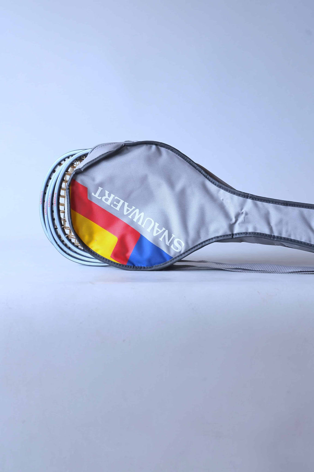 Close view of a vintage grey Snauwaert squash racket soft bag with a shoulder strap highlighting the red, yellow and blue brand logo.