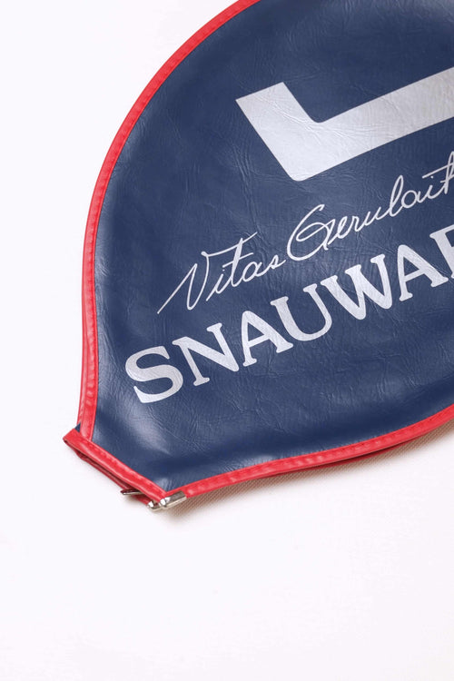 Close-up shot of the white printed Vitas Gerulaitis script signature and Snauwaert block text on a navy blue grained vinyl racquet cover with red stitched edges.