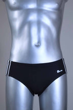 A pair of a Vintage Black men's swim briefs with white stripes on a metallic mannequin against a gray background