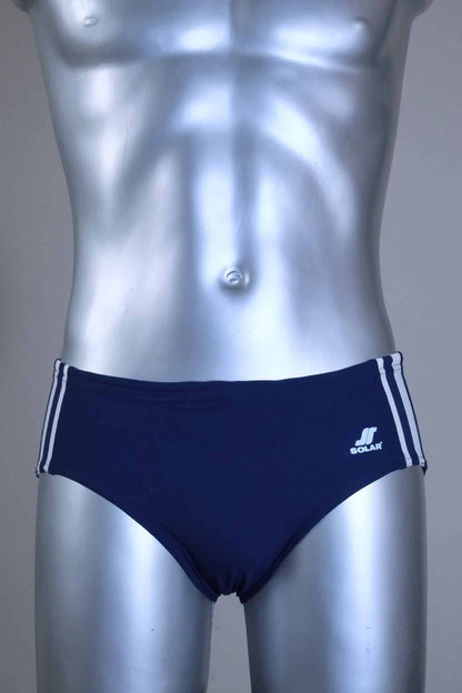 A pair of a Vintage navy men's swim briefs with white stripes on a metallic mannequin against a gray background