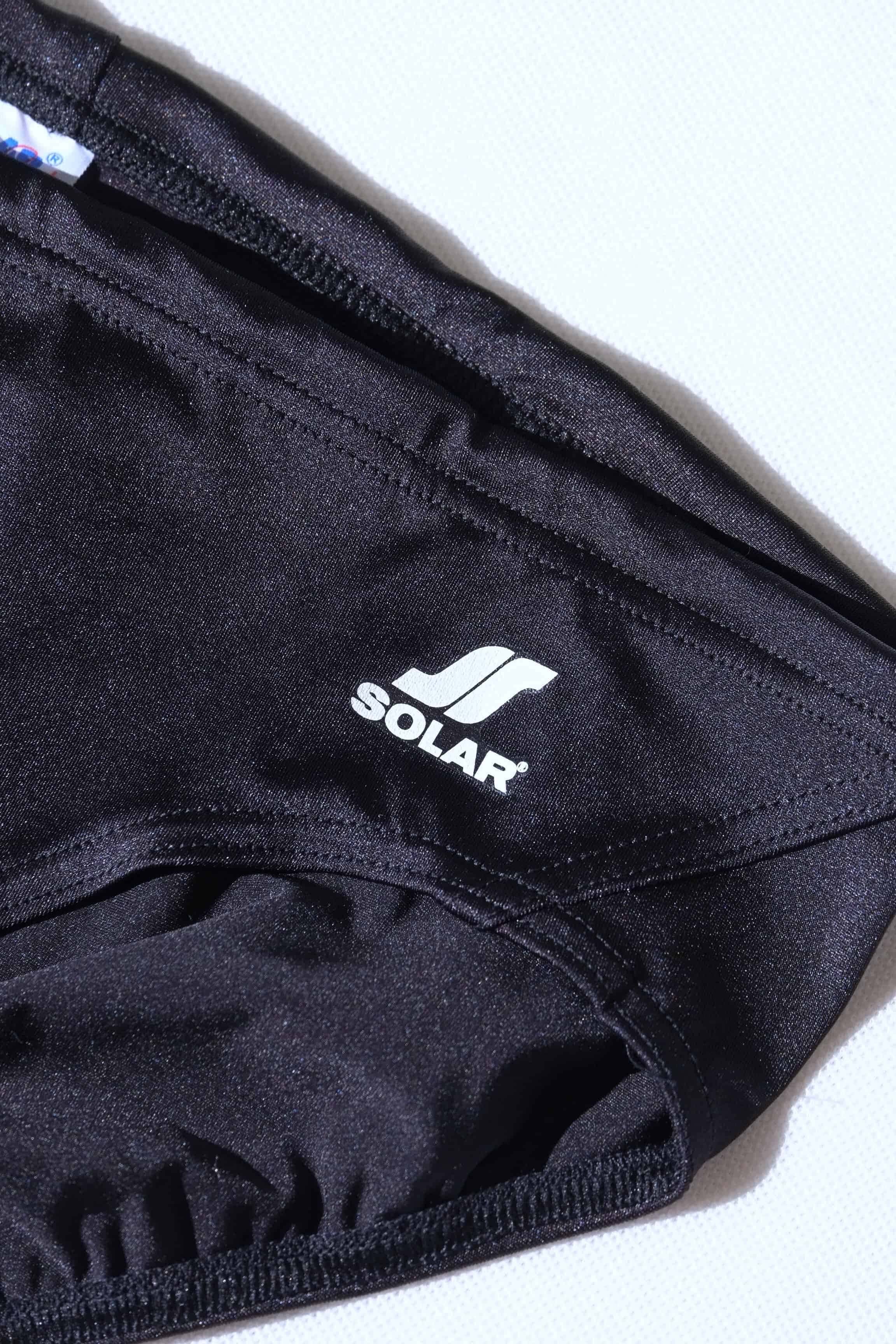 Close up of vintage Black swim briefs with Solar logo on a white background