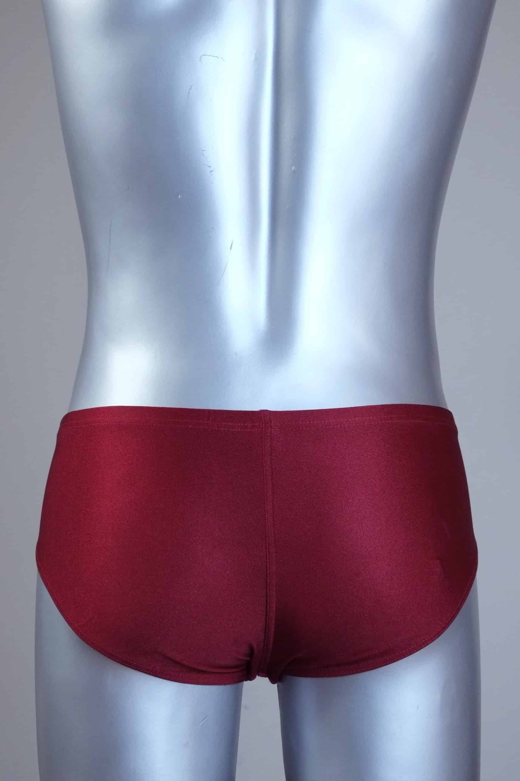Back view of a mannequin wearing a pair of vintage 70s burgundy swim briefs with a visible brand logo on a gray background