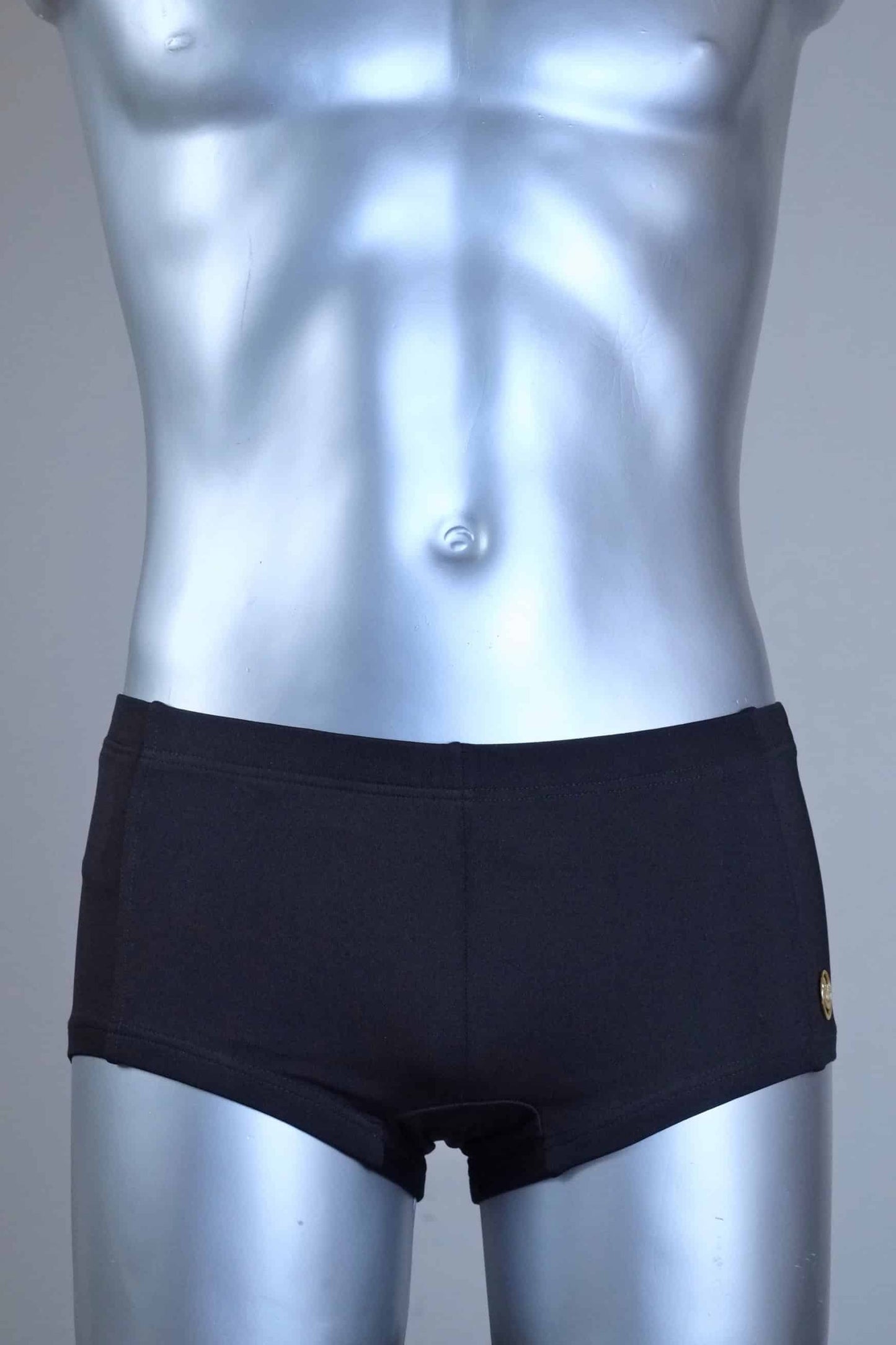 Mannequin wearing a pair of vintage 70s SOLAR swim trunks in black against a grey background.