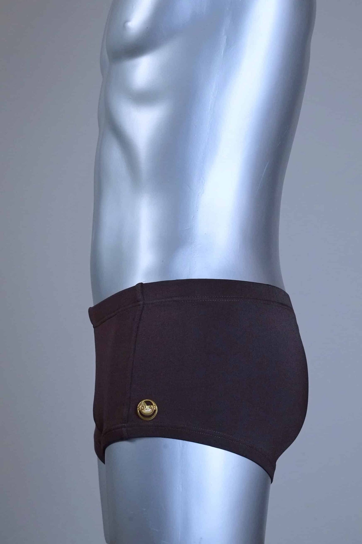 Side view of a Mannequin wearing a pair of vintage 70s SOLAR swim trunks in brown against a grey background.