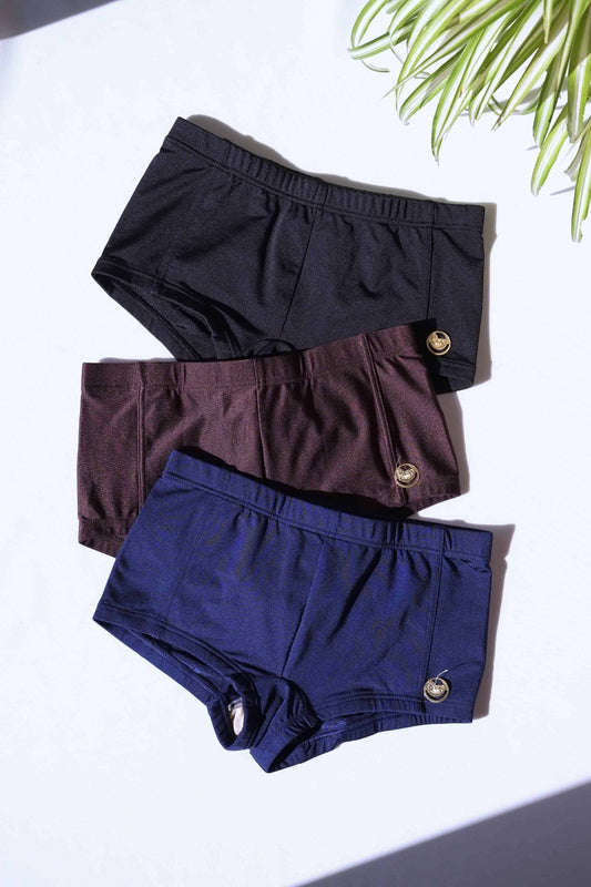 Set of three vintage 70s SOLAR swim trunks in black, brown, and navy with gold metal logo badge on each.