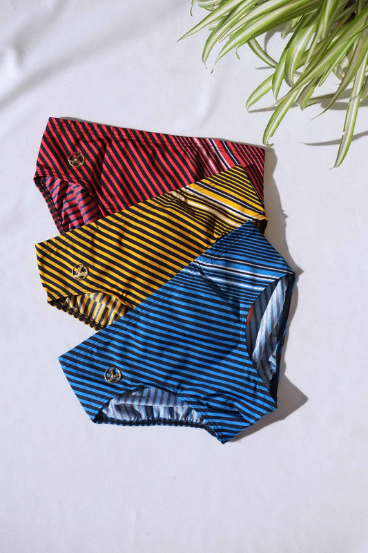 Three pairs of SOLAR brand vintage 80s men's swim briefs with horizontal and angled stripes in red, yellow, and blue, aid flat on a white background.