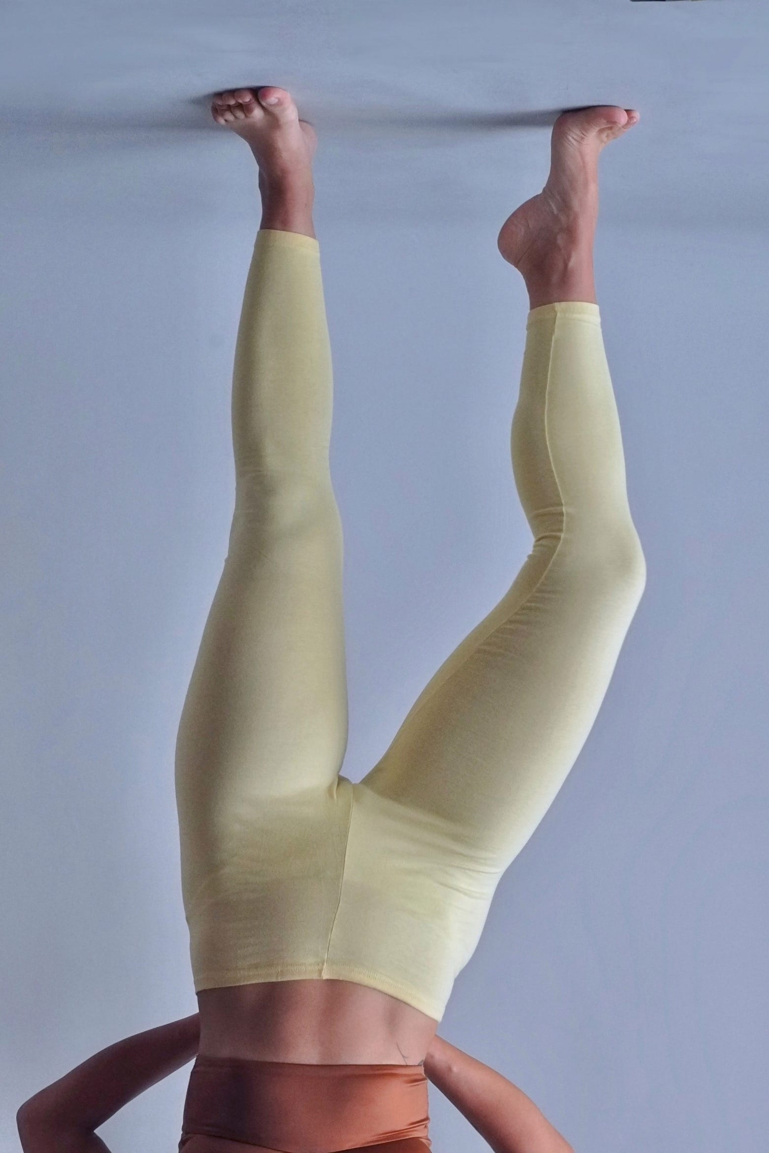 Solar vintage 80s solid cotton leggings in pale yellow worn on a female model — wide high-rise waistband, slim full-length cut, dynamic standing pose, front view