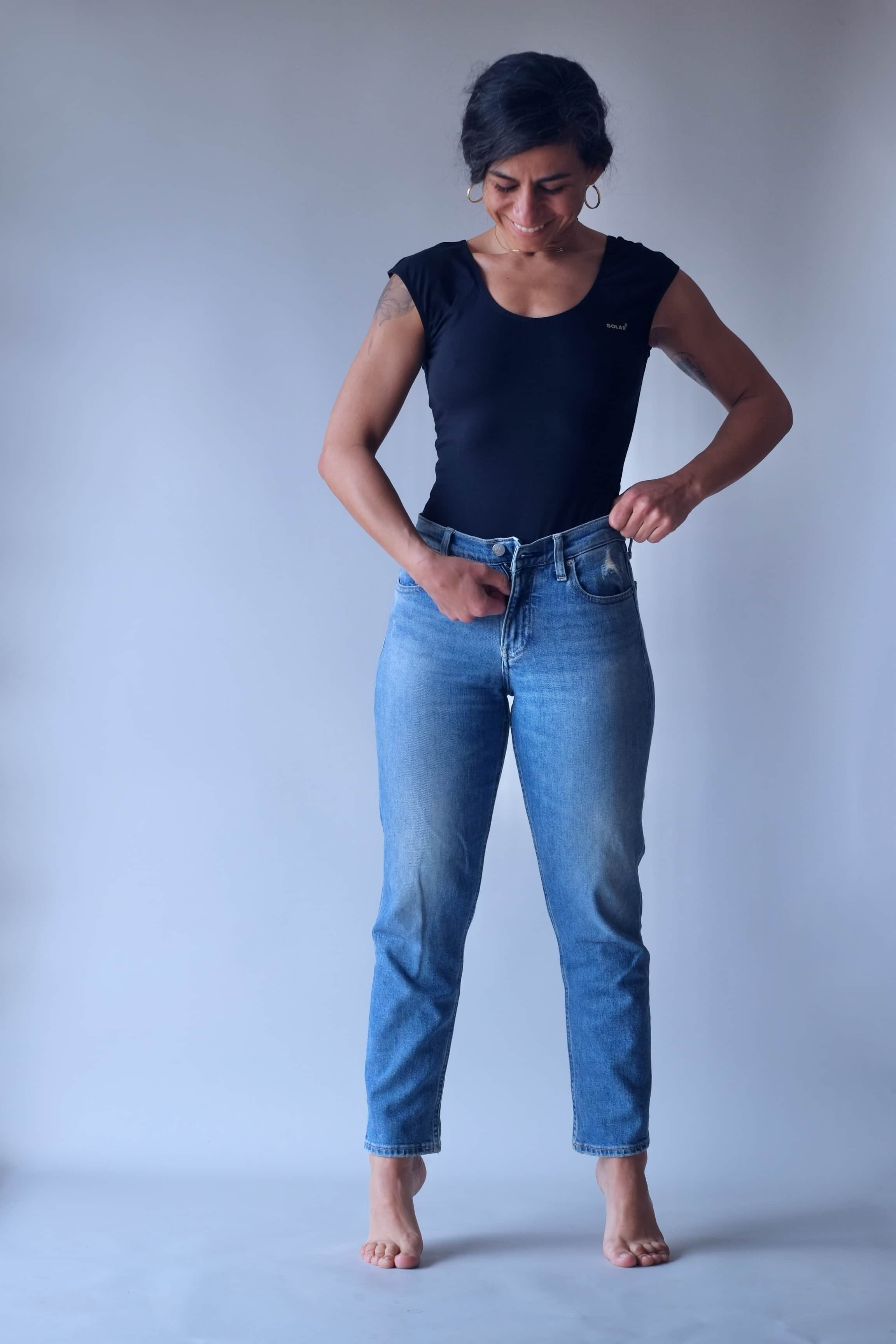 Solar vintage 80s solid black cap sleeve leotard worn on a female model — styled with light wash straight leg jeans, scoop neckline, cap sleeves, front view