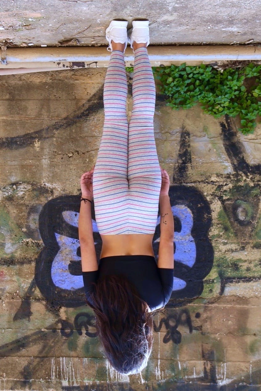 Solar vintage 80s micro stripe cotton leggings worn on a female model — fine pink and blue stripes on heather grey base, slim full-length cut, styled with white sneakers, rear view against urban wall backdrop